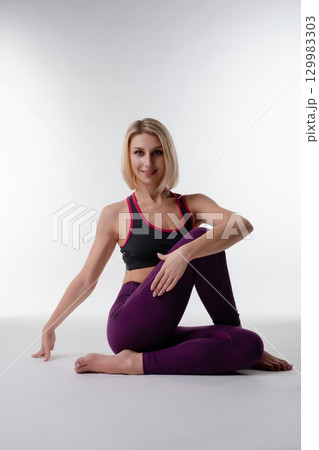 Yoga practitioner demonstrating split pose in a serene studio environment 129983303
