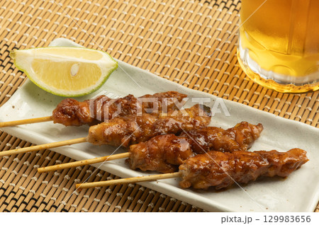美味しそうにてかっている焼き鳥とビールの注がれたジョッキ 129983656
