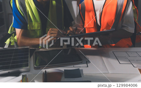 Closeup of team of industrial engineers meeting analyze machinery blueprints consult project on table in manufacturing factory. Working in manufacturing plant or production plant. 129984006