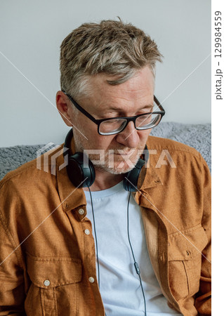 middle-aged man focused on task while wearing headphones in cozy indoor. closeup. middle-aged man focused on task while wearing headphones in cozy indoor. closeup. 129984559
