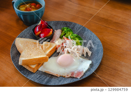 トーストや目玉焼き、ハムと野菜、果物を添えた洋風朝食プレート トーストや目玉焼き、ハムと野菜、果物を添えた洋風朝食プレート 129984759