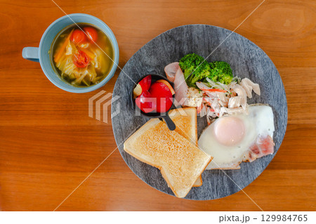 トーストや目玉焼き、ハムと野菜、果物を添えた洋風朝食プレート トーストや目玉焼き、ハムと野菜、果物を添えた洋風朝食プレート 129984765
