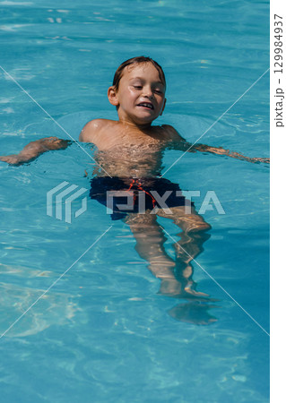A young boy is swimming in a pool A young boy is swimming in a pool 129984937