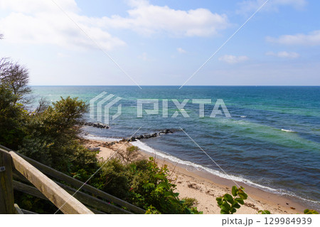 Sea shoreline with rocky breakwater and blue sky with clouds 129984939