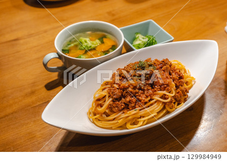 ミートソーススパゲッティと野菜スープ、きゅうりの小鉢を添えた夕食 129984949