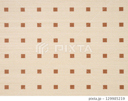 Warm beige veneer surface with a regular pattern of brown squares 129985219