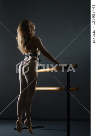 Captivating beauty in sensual pose against dark backdrop with soft lighting 129985441