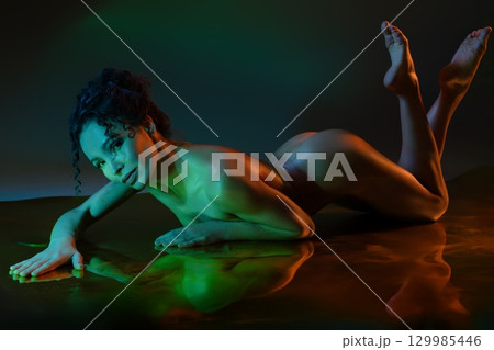 Elegant dancer performing a graceful pose in soft light and shadows Elegant dancer performing a graceful pose in soft light and shadows 129985446