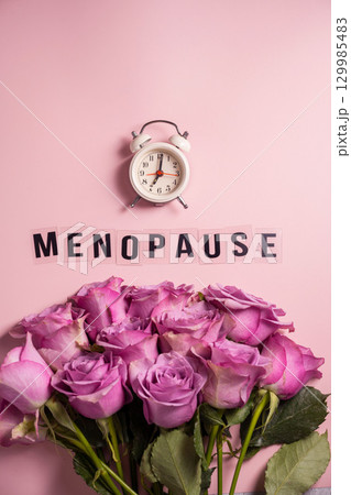 Word Menopause with pink roses and alarm clock, flat lay, pink background Word Menopause with pink roses and alarm clock, flat lay, pink background 129985483