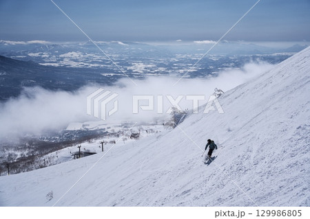 ニセコ東急 グラン・ヒラフ・ゲレンデのダイナミックコースからスキー場管理区域を滑るスキーヤー ニセコ東急 グラン・ヒラフ・ゲレンデのダイナミックコースからスキー場管理区域を滑るスキーヤー 129986805