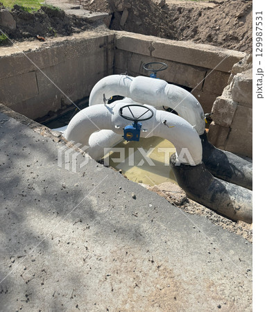 Installation of the distribution unit for the heating and water supply network. A frame for connecting pipes in an underground trench. Installation of the distribution unit for the heating and water supply network. A frame for connecting pipes in an underground trench. 129987531