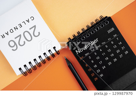 November 2026 desk calendar black and white color with pencil on orange color background. November 2026 desk calendar black and white color with pencil on orange color background. 129987970