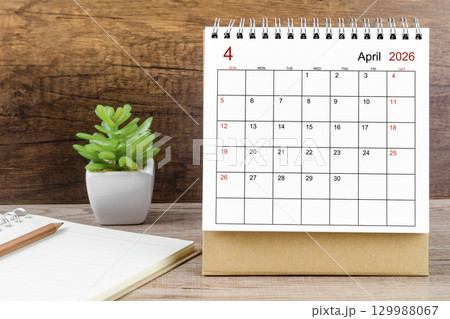 April 2026 desk calendar on the wooden worktable. 129988067
