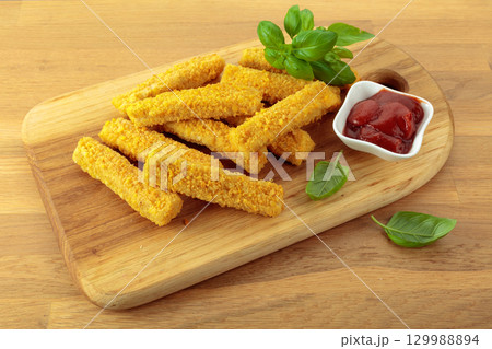 Cheese sticks with basil and ketchup on a wooden table. 129988894