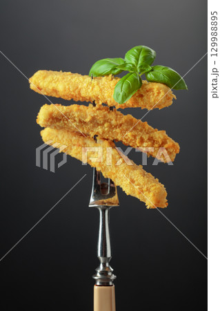 Cheese sticks with basil on a fork. Cheese sticks with basil on a fork. 129988895