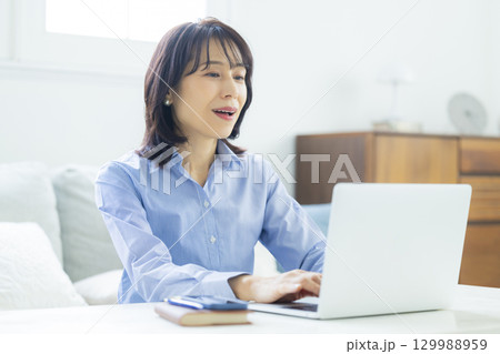 リビングでテレワーク中のミドル女性 リビングでテレワーク中のミドル女性 129988959