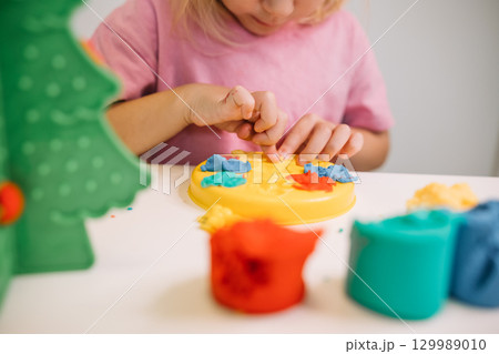 A child creating colorful designs with play dough at home in a cheerful indoor setting 129989010