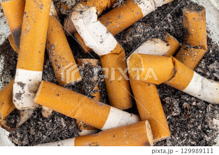 Closeup of cigarette butt and ashes on a plain background 129989111