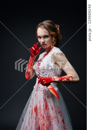 Woman in bloodied wedding dress wields katana, embodying eerie beauty and danger Woman in bloodied wedding dress wields katana, embodying eerie beauty and danger 129989248