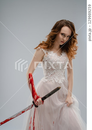 Lingerie-clad bride wielding a katana with bloodstains in a striking pose Lingerie-clad bride wielding a katana with bloodstains in a striking pose 129989259