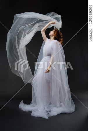 Elegant beauty draped in white fabric evokes bridal and princess themes Elegant beauty draped in white fabric evokes bridal and princess themes 129989266