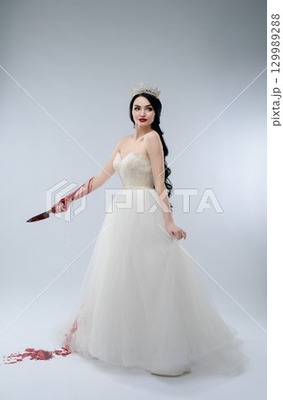 Bridal beauty in white gown holds knife with blood for dramatic effect Bridal beauty in white gown holds knife with blood for dramatic effect 129989288