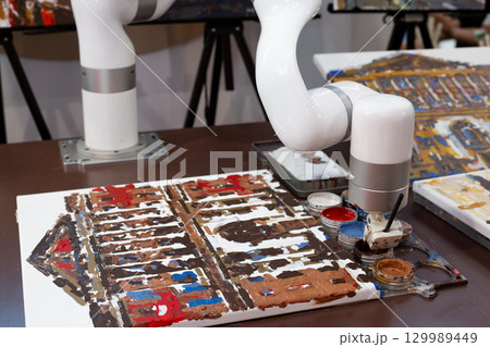 Robotic arm painting on canvas, symbolizing automation replacing human creativity. Representation of artificial intelligence competing with humans in art and design professions Robotic arm painting on canvas, symbolizing automation replacing human creativity. Representation of artificial intelligence competing with humans in art and design professions 129989449