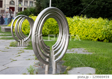 Modern stainless steel bicycle rack in an urban park. Designed for secure bike parking, offering cyclists a convenient and safe place to lock their bicycles while visiting public spaces 129989459
