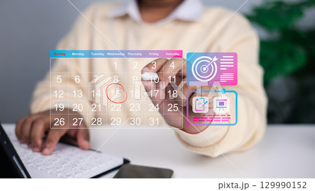 Close up of person using transparent digital calendar with highlighted date and floating icons for goals, task management, and project planning, concept of time management and productivity. 129990152