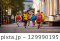 Children with colorful backpacks walking to school on a sunny morning street 129990195