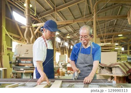 シニア職人が木材を確認する工場内の作業風景 129990313
