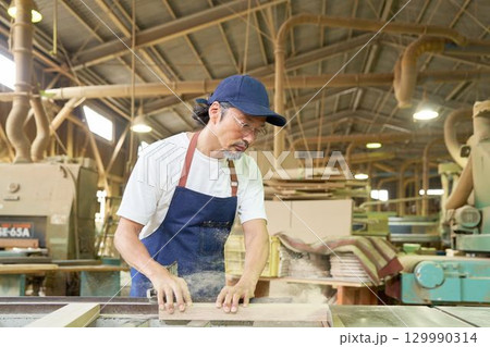 丸鋸盤で木材を切断するシニア職人 丸鋸盤で木材を切断するシニア職人 129990314