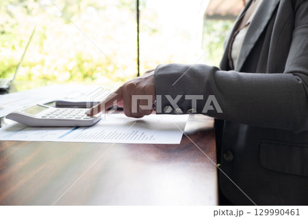 Businesswoman, entrepreneur, accountant working on financial report on desk using calculator, laptop. Businesswoman, entrepreneur, accountant working on financial report on desk using calculator, laptop. 129990461