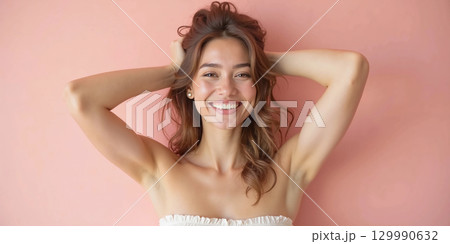 Smiling young woman posing playfully against pink background in casual summer outfit Smiling young woman posing playfully against pink background in casual summer outfit 129990632