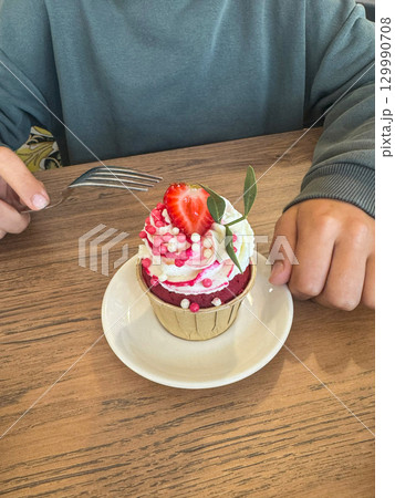 Juicy strawberry cupcakes crowned with airy whipped cream and decorated with vibrant fresh strawberries, offering a delightful blend of flavor and visual appeal ideal for summer treats. 129990708