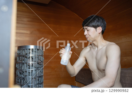 サウナで水を飲む男性 129990982