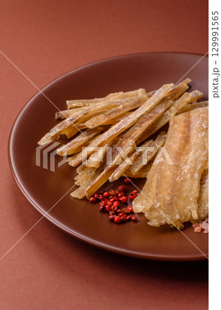 Dried salted fish, snacks or jerky, slices of white fish fillets 129991565