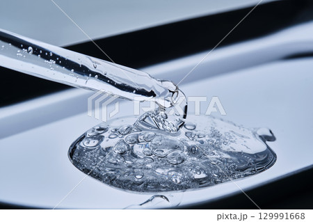 A pipette with cosmetic serum on a blue background. 129991668