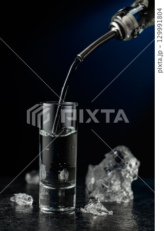 Crystal clear vodka or gin being poured into a glass. Crystal clear vodka or gin being poured into a glass. 129991804