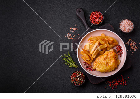 Fried French fries with a piece of meat, lunch food. Prepared potatoes and meat 129992030
