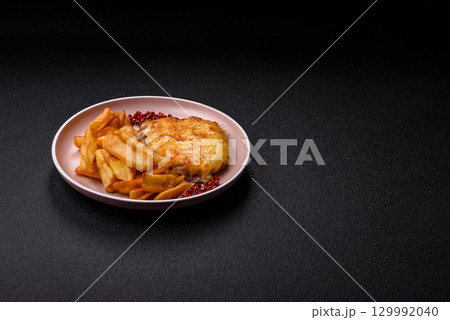 Fried French fries with a piece of meat, lunch food. Prepared potatoes and meat 129992040