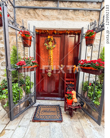 Decorated wooden door with floral wreath and seasonal details. Home entrance, culture, hospitality, tradition and lifestyle in a historic European town. 129992183