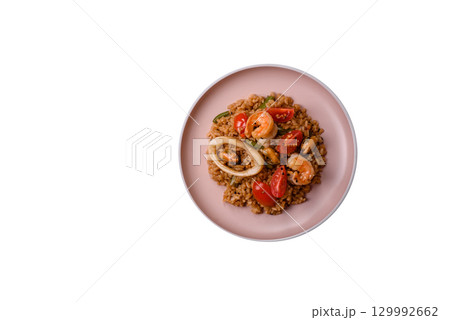 Rice and prawns or paella, a meal with seafood and vegetables. Cooked rice with shrimp Rice and prawns or paella, a meal with seafood and vegetables. Cooked rice with shrimp 129992662