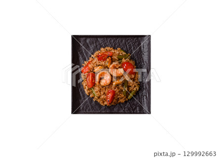 Rice and prawns or paella, a meal with seafood and vegetables. Cooked rice with shrimp Rice and prawns or paella, a meal with seafood and vegetables. Cooked rice with shrimp 129992663