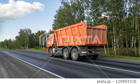 Dumper truck on the road. Construction equipment is driving on the highway. A car with a body to carry loose material. 129993316