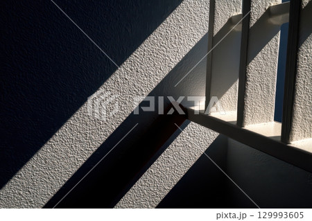Geometric shadow play on minimalist white wall from blinds abstract architectural composition 129993605