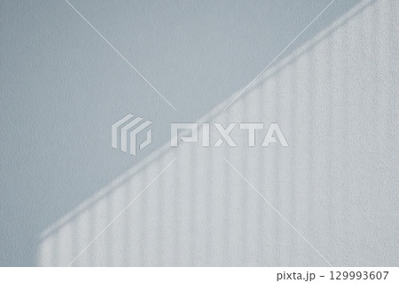 Geometric shadow play on minimalist white wall from blinds abstract architectural composition 129993607