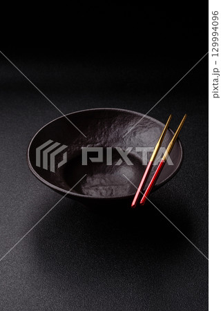 Empty round black plate for food, risotto or pasta. Empty plate on dark background Empty round black plate for food, risotto or pasta. Empty plate on dark background 129994096