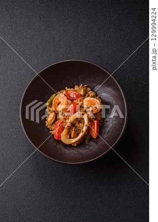 Rice and prawns or paella, a meal with seafood and vegetables. Cooked rice with shrimp 129994224