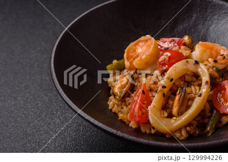 Rice and prawns or paella, a meal with seafood and vegetables. Cooked rice with shrimp Rice and prawns or paella, a meal with seafood and vegetables. Cooked rice with shrimp 129994226